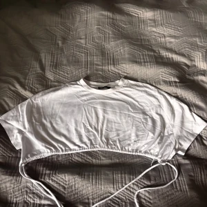 Vit croppad topp med snörning - Säljer en vit croppad topp från Zara med korta ärmar. Toppen har snörning i nederkanten så du kan justera passformen. Perfekt till jeans eller kjol-jätteenkel att styla.