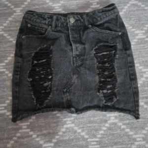 Svart jeanskjol med slitningar  - Fint skick. Midja 34cm, Längd 35cm