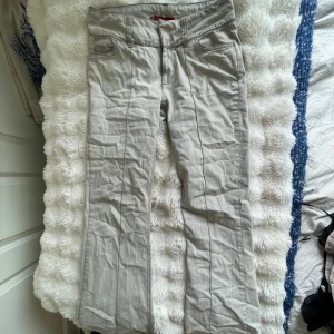 Beiga bootcut byxor från Only - Säljer ett par beiga bootcut-byxor från Only med rå kant nertill för en edgy vibe. Byxorna har klassiska fickor fram, markerad söm längs benen och är tillverkade i ett mjukt bomullsmaterial. Perfekta för dig som gillar en avslappnad men trendig look.