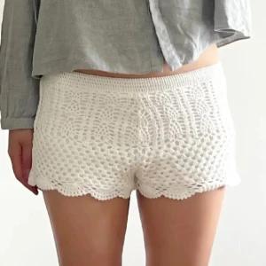 Vita virkade shorts med spetskant - Superfina vita virkade shorts med snygg spetskant nertill och elastisk midja. De har ett unikt mönster och känns riktigt somriga och lätta. Perfekta för varma dagar när du vill ha något luftigt och trendigt.