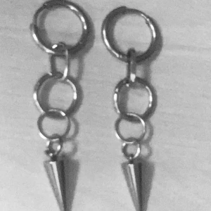 Silvriga örhängen med kedjor och spikes - Coola silvriga örhängen med ringar i kedjeform och spetsiga spikes längst ner. Ger en edgy vibe och passar perfekt för dig som gillar statement-smycken. Metallisk finish och modern design.