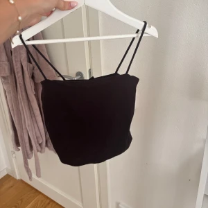 Svart croppad linnetopp från Gina Tricot - Snygg svart croppad linnetopp från Gina Tricot med tunna axelband. Haft i flera år men sparsamt använt. Strl xs. Pris 20 kr. 