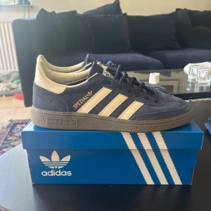 Adidas Spezial sneakers marinblå/vit mocka - Säljer ett par Adidas Spezial sneakers i marinblå mocka med klassiska vita ränder och detaljer. Skorna har snörning, platt sula och rund tå. Perfekta för dig som gillar retrostil och vill sticka ut med en ikonisk modell.