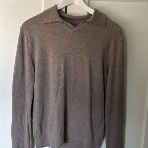 Beige merinoullströja These Glory Days - Säljer en stilren beige långärmad tröja från These Glory Days i mjuk merinoull. Tröjan har klassisk krage med v-ringning och en clean look som passar perfekt till jeans eller chinos. Skön passform och riktigt snygg färgton.