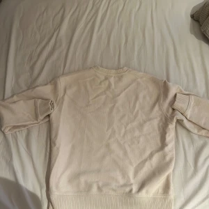 Beige stickad tröja från Zara - Snygg beige stickad tröja från Zara med rund halsringning och ribbade muddar vid ärmslut och nederkant. Enkel och stilren design som passar perfekt till jeans eller kjol. Mjuk och skön känsla, perfekt för lager-på-lager under kyliga dagar.