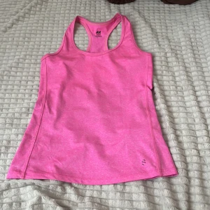 Rosa sporttopp  - Säljer en snygg rosa sporttopp från H&M i storlek XS. Toppen är tillverkad i ett stretchigt material som passar perfekt för träning. Den har en enkel, sportig design och är riktigt bekväm att ha på sig. Super skick!
