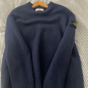 Mörkblå tröja från Stone Island - Säljer en snygg mörkblå tröja från Stone Island. som jag köpte ifrån en kille på plick. Tröjan har långa ärmar och en klassisk design med ribbstickade muddar. Perfekt för kyligare dagar. Det står storlek M men det är garanterat en S.  PRIS KAN DISKUTERAS 