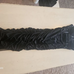 Svart långklänning från SHEIN - Snygg svart långklänning från SHEIN i storlek M. Klänningen har en åtsittande passform med draperade detaljer längs hela längden och tunna axelband. Perfekt för dig som vill sticka ut med en elegant och stilren look.