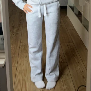 Gråa mjukisbyxor med knyt i midjan RUSSEMERCH  - Säljer ett par ljusgrå mjukisbyxor med normal passform och knytband i midjan. Byxorna har raka ben och är perfekta för en chill och avslappnad stil. Supermjuka och sköna, passar perfekt till hoodie eller t-shirt.