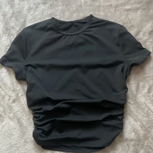 Svart t-shirt från SHEIN XS - En basic svart t-shirt från SHEIN i storlek XS. T-shirten har rund halsringning och korta ärmar. Materialet känns mjukt och stretchigt, perfekt för en clean och enkel look. Passformen är normal och tyget är slätt utan mönster.