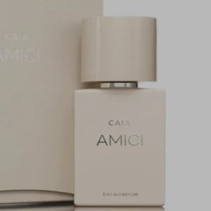 CAIA Amici Eau de Parfum - Snygg parfymflaska från CAIA i modellen Amici. Flaskan är stilren och rektangulär i en matt beige färg med matchande lock. Texten är i silver och svart, vilket ger en lyxig känsla. Perfekt för dig som gillar minimalistisk design.
