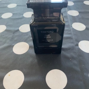 Tom Ford Oud Wood Eau de Parfum 100 ml - Säljer en exklusiv Tom Ford Oud Wood Eau de Parfum i en elegant svart flaska på 100 ml. Doften är känd för sina rika och mystiska noter av oud, vilket ger en lyxig och sofistikerad känsla. Perfekt för den som vill ha en unik och minnesvärd doftupplevelse pris kan diskuteras.