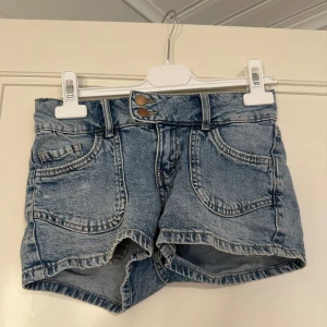 Blå jeansshorts från Lindex - Snygga blå jeansshorts från Lindex med dubbla metal knappar fram. Säljer pågrund av att jag inte direkt fått någon användning av de när jag har ett annat liknande par som passar mig bättre.