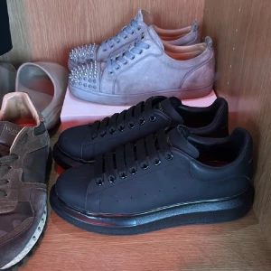 Svarta sneakers från Alexander McQueen - Stilrena svarta sneakers från Alexander McQueen med chunky platt sula och rund tå. Skorna har diskret guldlogga på hälen och klassisk snörning. Tillverkade i skinn med en clean look som passar till allt. Perfekta för dig som gillar exklusiva och trendiga sneakers.