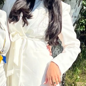 Vit kavaj med bälte från Fidosa - Vit kavaj till salu! Endast använd en gång på student, har en liten blå fläck på armen som förmodligen kan gå bort vid tvättning men säljer den ändå jätte billigt. Köpt från turkiet och är i storlek 38