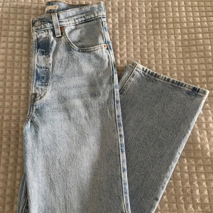 Levi's jeans - Ribcage straight  - Klassiska Levi's 501 jeans i ljusblå tvätt med raka ben och hög midja. Jeansen har fem fickor, knappgylf och den ikoniska läderpatchen bak. Tillverkade i robust denim av bomull, perfekt för en avslappnad och tidlös look.