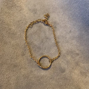 Guldigt armband med cirkel! - Stilrent armband i guldton med tunn kedja och en enkel cirkel i mitten. Justerbar längd med karbinlås. Totala längden inklusive knäppe 21 cm