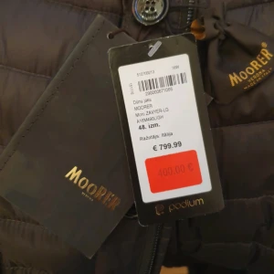 Brun dunjacka från MooRER Verona - Snygg brun dunjacka från MooRER Verona med quiltad design och klassisk kavajkrage. Jackan har knappar framtill, dragkedja och fickor med lock. Tillverkad i 100% gåsdun för extra värme och lätt känsla. Perfekt för dig som vill ha stil och funktion i ett.