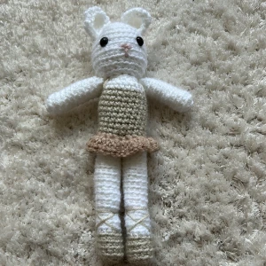 Beige virkad klänning till docka - Söt virkad klänning i beige med volangkant i ljusbrun, perfekt till en mjukisdocka eller amigurumi. Klänningen är ärmlös och har en enkel, rak passform med liten kjol. Materialet är mjukt och stickat för en gullig look./Ai