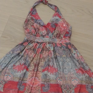 Mönstrad halterneckklänning Ilse Jacobsen - Färgstark halterneckklänning från Ilse Jacobsen i storlek S. Klänningen har v-ringning, knyt i nacken och ett vackert paisleyinspirerat mönster i rosa, blått och beige. Orginalpris ca 1500