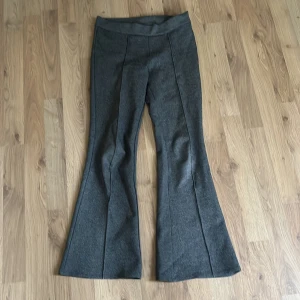 Grå bootcut byxor - Mörkgrå bootcut-byxor i mjukt stretchigt material. Byxorna har hög midja och markerade sömmar framtill som ger en snygg siluett.