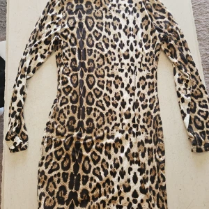 Leopardmönstrad klänning från SHEIN - Snygg leopardmönstrad klänning från SHEIN i storlek L. Klänningen har långa ärmar och är figurnära med kort längd. Materialet är mjukt och stretchigt, perfekt för dig som vill sticka ut med ett djurmönster.