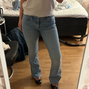 Ljusblå bootcut jeans - Säljer ett par ljusblå jeans med klassisk femficksdesign och bootcut passform. Jeansen har låg midja och är tillverkade i mjukt denimtyg som sitter snyggt över höfterna och låren. Perfekta för dig som gillar en avslappnad men ändå stilren look.