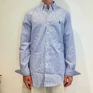 Randig Ralph Lauren Skjorta - Vit/ blå randig Ralph lauren skjorta || Storlek M (Slim Fit) || Skjortan är i bra skick || Mitt pris 599kr || Modellen på bilden är 170cm och väger 62kg || Tveka inte på att höra av dig vid frågor eller funderingar 