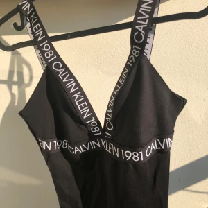 Svart body från Calvin Klein - Svart body från Calvin Klein. Djup v-ringning bak och v formad urringning i fram. Använd kanske 2-3 gånger. Den är M men passar S oxå. Den är gjord i tyg men går att använda som baddräkt oxå tycker jag.