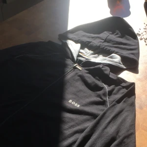 Hugo Boss zip hoodie - Svart zip hoodie från Hugo Boss. Den är inte så tjock, därför är den perfekt för sommaren och kallare sommar kvällar. Svart/grå färg ◼️⬜️, Storlek: S ✅Nyskick, använd 1 gång 👌