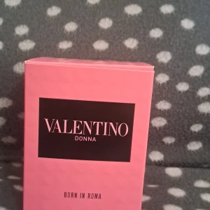Valentino Donna Born In Roma parfym - Lyxig parfym från Valentino, Donna Born In Roma. Flaskan är fyrkantig med nitar och har en rosa tonad vätska. Snygg svart kork med nitar och matchande rosa och svart kartong. Perfekt för dig som gillar exklusiva dofter och snygg design.
