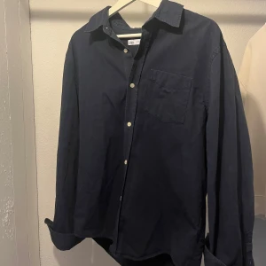 Zara skjortor i bomull, marinblå & vit - Två stilrena skjortor från Zara i storlek M, en marinblå och en vit. Båda har klassisk krage, bröstficka och knäppning framtill. Perfekta för en clean och enkel look. En för 200 kr, eller båda för 350kr.