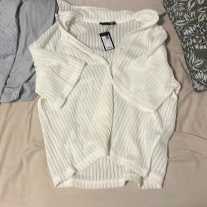 Vit ribbad skjorta Smith knitted Braid - Vit skjorta från Smith i ribbat stickat material. Skjortan har korta ärmar, knappar framtill och en avslappnad passform. Perfekt för dig som gillar en luftig och chill stil. Snyggt randigt mönster i strukturen och mjuk känsla mot huden. Inte använd 