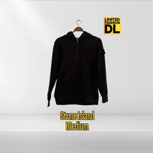 Stone Island Hoodie stl Large - Svart hoodie från Stone Island med dragkedja framtill, huva med snörning och klassisk logga på vänster ärm. Tillverkad i mjuk bomull och har två fickor fram. Perfekt för dig som gillar streetwear och vill ha en clean look.