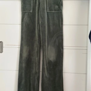 Gröna Juicy Couture byxor - Mörkgröna mjukisbyxor från Juicy Coutur. Byxorna har raka ben  med silverfärgade knappar och broderad logga. 