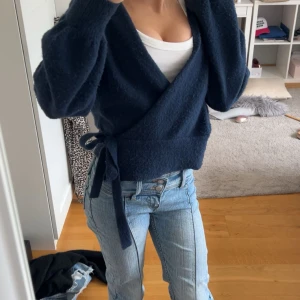 Mörkblå omlottkofta med knytband - Säljer en mörkblå stickad omlottkofta med knytband i midjan. Koftan har v-ringning och långa ärmar med lite loose passform. Perfekt att slänga över ett linne eller t-shirt för en chill look. Orginal pris 800🩷