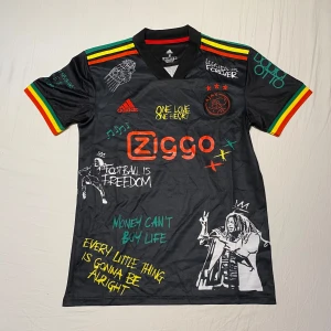 Ajax fotbollströja  - Ajax fotbollströja i nyskick. Inga defekter alls, fin fotbollströja för sommaren med snygg design över hela T-shirten.Ajax fotbollströja i nyskick. Inga defekter alls, fin fotbollströja för sommaren med snygg design över hela T-shirten.