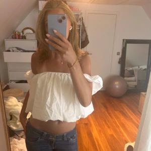Vit offshoulder croppad topp - Superfin vit offshoulder topp med voluminösa ärmar och croppad passform. Luftig och lätt, perfekt för varma dagar. Snygg att styla med jeans eller kjol för en trendig look.