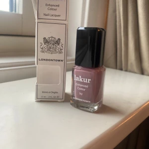 Londontown Lakur Bell Flower nagellack - Nagellack från Londontown i nyansen Bell Flower, en mjuk och trendig lila-rosa ton. Kommer i en stilren glasflaska med svart fyrkantigt lock. Innehåller 12 ml och ger en elegant finish till naglarna. Nypris 200kr helt oöppnad 