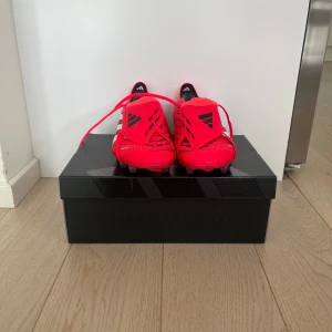 Adidas Predator röda fotbollsskor - Helt nya Adidas predator som har skick 10/10. Skorna har en plös som du drar under dobbarna.