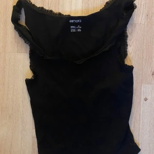 Svart linnetopp med spets från Esmara - Snygg svart linnetopp från Esmara med spetsdetaljer längs kanterna. Toppen är ärmlös och har en mjuk, bekväm känsla som passar perfekt till jeans eller kjol. Enkel men ändå elegant design som lyfter din outfit.
