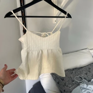 Topp från Gina - Supersöt ljusbeige linnetopp med tunna axelband och knytning i ryggen. Från Gina Tricog