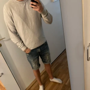 Ljusgrå bomullströja med struktur - Säljer en stilren ljusgrå tröja med diskret strukturerat mönster. Tröjan har rund halsringning och långa ärmar med ribbade muddar. Perfekt för dig som gillar en clean och enkel look. Materialet känns mjukt och skönt mot huden. Passar även m