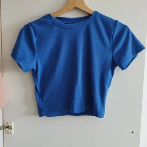 Blå ribbad croppad topp - En enkel men snygg blå croppad topp med ribbad struktur och korta ärmar. Perfekt för dig som gillar en stilren look med lite edge. Passar till både jeans och kjol för en chill vibe.Kan hämtas upp i Malmö 