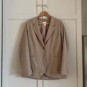 Beige blazer från H&M - Snygg beige blazer från H&M som går att stänga med en knapp. Normal passform. Storlek M. 