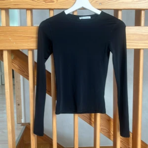 Svart långärmad topp från Zara - En stilren svart långärmad topp från Zara i storlek S. Modellen är figurnära med rund halsringning och tillverkad i ett mjukt, stretchigt syntetmaterial som känns skönt mot huden. Perfekt att styla med jeans eller kjol för en clean look. Materialet är polyamid.