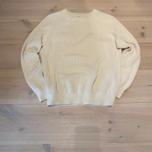 Stickad tröja - Säljer en stilren beige stickad tröja med rund halsringning. Tröjan har långa ärmar och ribbade muddar vid ärmslut och nederkant. Perfekt för lager-på-lager och enkel att matcha med olika outfits. Skicka ett meddelande för frågor, storlek, mått osv. 