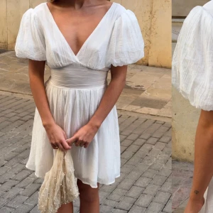 Vit klänning - Helt ny med prislapp, superfin vit kortklänning med v-ringning, puffiga kortärmar och markerad midja. Klänningen har en stor rosett i ryggen. (Man knyter den som man själv vill). PERFEKT TILL STUDENTEN! 🌸