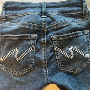 Mörkblåa jeans - Mörkblå jeans från Nelly med vita broderingar i bak på fickorna. De är i jätte fint skick endast lite nötta längst ner i bak, se bild ovanför. Skriv för fler frågor, bilder m.m