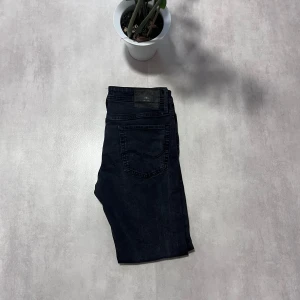 Svarta jeansbyxor - Säljer ett par svarta jeansbyxor med klassisk femficksdesign och normal passform. Byxorna har en enkel look utan synliga detaljer och passar till många olika stilar.